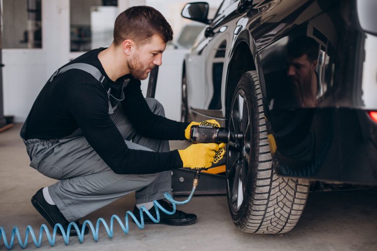 Car mechanic changing wheels in car